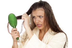young nervous woman in bathrobe brush her moist hair